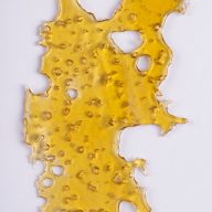 A piece of cannabis oil concentrate aka shatter isolated against white background