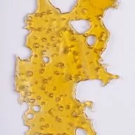 A piece of cannabis oil concentrate aka shatter isolated against white background