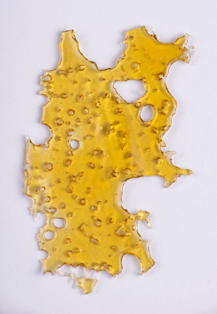 A piece of cannabis oil concentrate aka shatter isolated against white background