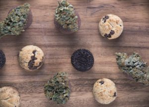 Order Lab-tested CBD Cookies in Canada. Background with cannabis nugs (forum cut cookies strain) over infused chocolate chips cookies - medical marijuana edibles concept